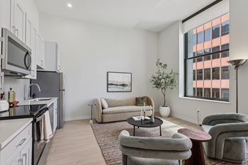 A modern kitchen with a large window and a living room area with a couch and chairs at LiveWell Apartments, Pennsylvania, 15222